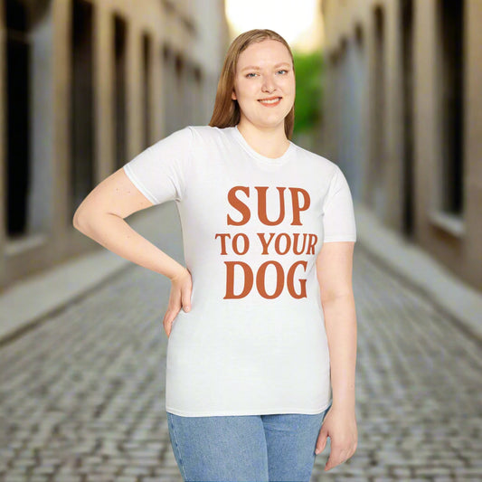 Woman wearing white t-shirt with burnt orange text that says “SUP TO YOUR DOG”