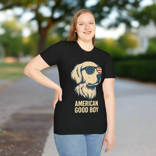 Woman wearing a black t-shirt featuring a golden retriever-style dog with patriotic sunglasses and the text “American Good Boy” in bold vintage lettering